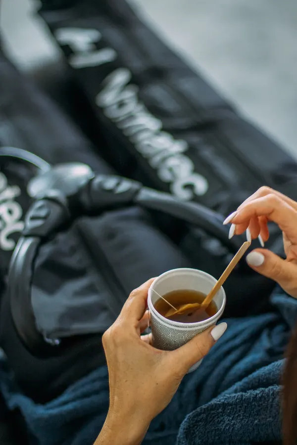 Tasse de thé tendue à la cliente pendant la pressothérapie