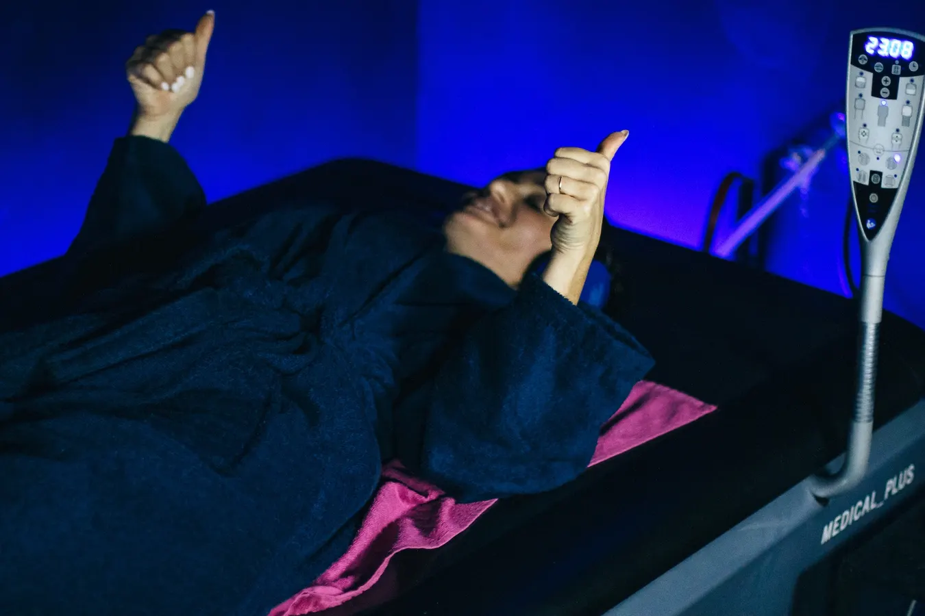 Cliente allongée sous une lumière bleue, pouce levé